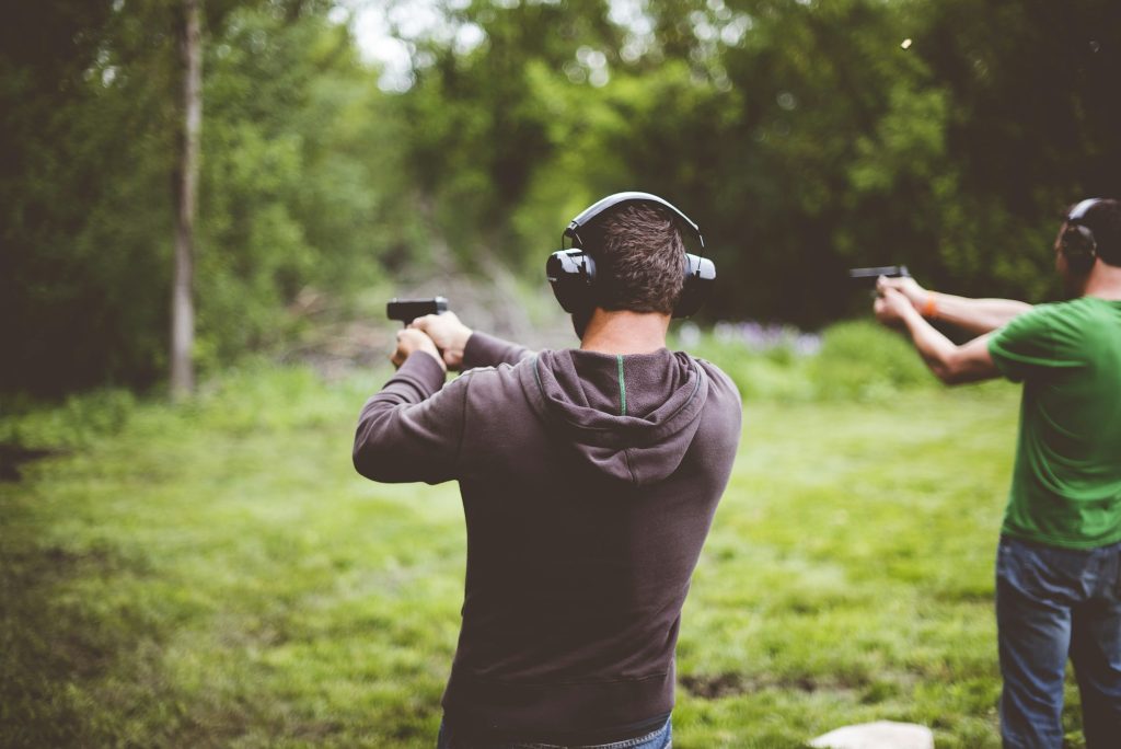 Shallow focus shot of people shotting guns in nature